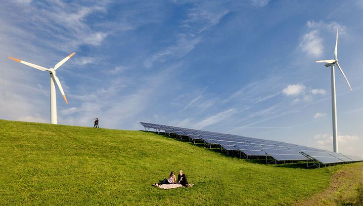 Windräder und Solarzellen auf einer grünen Wiese